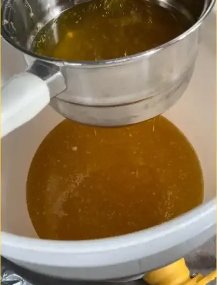 Coulée de miel doré dans une passoire de métal